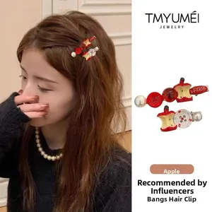 Detail of red apple bead hair clips and pearl pins worn on hair side for styling