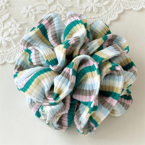 Detail of colorful striped oversized scrunchie with soft ribbed knit texture and pastel tones