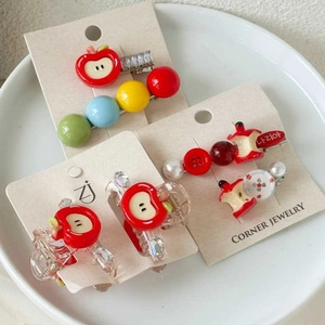 Detail of sweet apple-themed hair clips with colorful beads on a ceramic tray