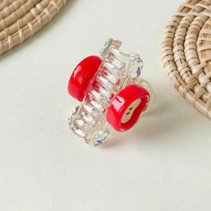 Detailed close-up of a mini red apple hair claw clip with clear acrylic and rhinestones