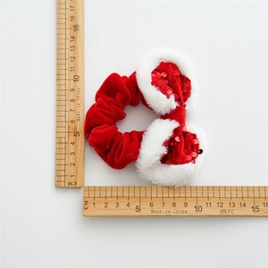 Red velvet Christmas scrunchie with white faux fur and sequins being measured on a ruler