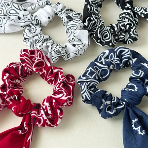 Detailed view of paisley bow hair scrunchies in red, navy, black and white patterns