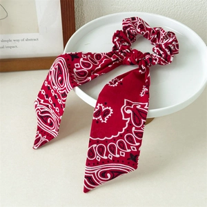 Detail of red paisley print hair scrunchie with long ribbons on a display tray