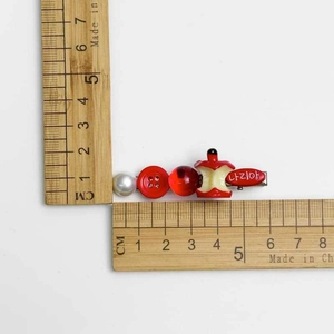Detailed macro view of creative apple beaded hair clip showing 5.5cm length on ruler