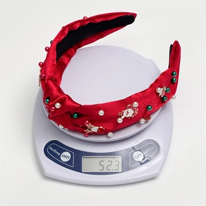 Detail showing red Christmas headband with pearls and charms on a digital scale weighing 52.3g
