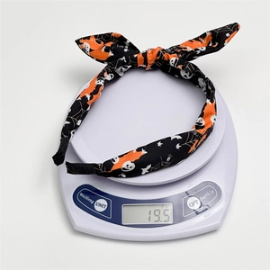 Detail showing a lightweight Halloween headband with ghost and bat prints on an electronic scale