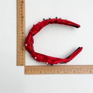 Christmas red knotted headband with pearls and gold accents measured on a ruler