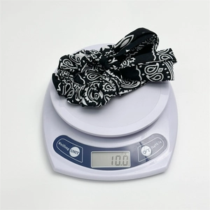 Detail shot of paisley print hair scrunchie with bow showing 10g weight on scale