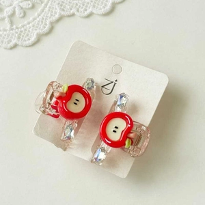 Close-up of cute red apple hair clips with pink transparent finish on white lace background
