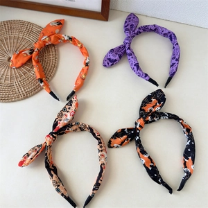 Detail of four Halloween rabbit ear headbands with pumpkin and bat prints in festive colors