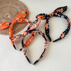 Three Halloween bunny ear headbands with skull and pumpkin prints on festive orange and black fabric