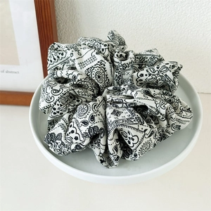 Detailaufnahme eines großen Scrunchie mit Paisley-Muster auf weißem Keramiktablett