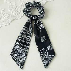 Close-up of black and white paisley print hair scrunchie with long ribbons on lace background