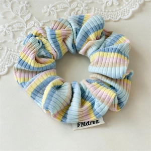 Close-up of ribbed knit scrunchie with pastel stripes and white FMdrea brand tag