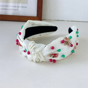 Detail of Christmas headband with pearls and reindeer charms on white satin knot