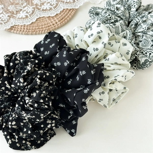 Detail von vier Haargummis aus Chiffon mit Paisley- und Gänseblümchenmustern