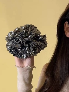 Macro shot of oversized silver metallic scrunchie with pleated texture and ruffle detail