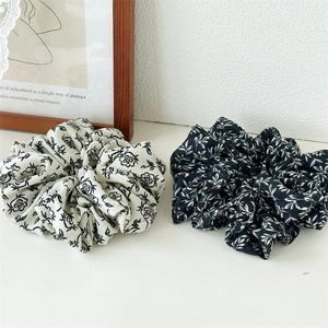 Set of two large scrunchies with ink rose floral and white leaf patterns on a white surface