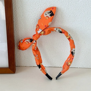 Detail of orange Halloween headband with pumpkin and ghost prints and bunny ear bow knot