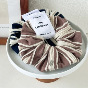 Close-up of navy and chocolate striped knit scrunchies with elegant metal charms