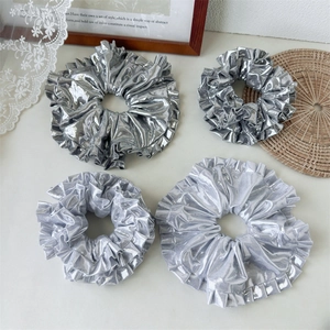 Close-up of silver laser-textured hair scrunchies with pleated ruffle edges and shiny finish