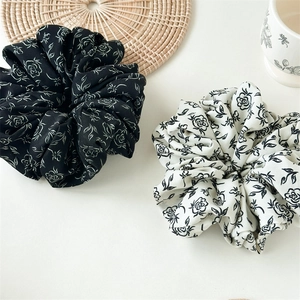 Macro view of large ink rose print scrunchies in elegant black and white floral patterns
