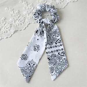Detailed close-up of a white paisley print scrunchie with long ribbons and elegant lace