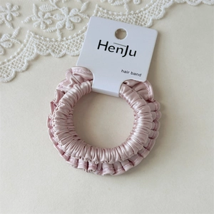 Detail of dusty pink satin scrunchie showing glossy pleated silk texture and card