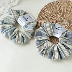 Close-up of blue and grey striped fabric scrunchies on a minimalist background