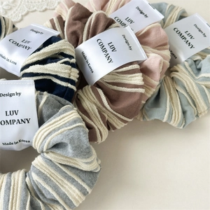 Set of five striped fabric scrunchies in pastel tones with a minimalist design labels