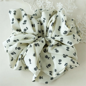 Detailansicht eines cremefarbenen Blumen-Scrunchie aus Chiffon mit eleganten Falten
