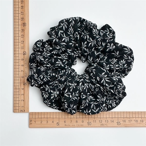 Ink print scrunchie with white leaf pattern on black chiffon shown with size scale ruler