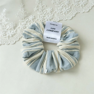 Detailed shot of striped blue scrunchie with designer label and lace accessory