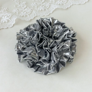 Macro detail of the silver laser fabric layers and metallic texture of the oversized scrunchie