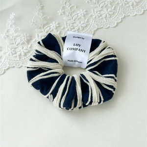 Detailed close-up of navy blue striped cotton scrunchie with lace trim and woven label