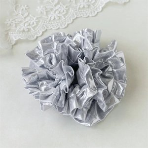 Close-up of metallic silver pleated scrunchie with reflective hydrangea flower effect