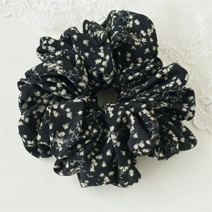 Detailaufnahme des schwarzen Chiffon-Haargummis mit feinem weißem Blumenmuster