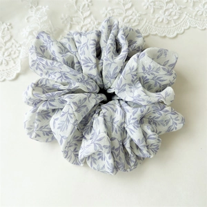 Close-up of elegant floral scrunchie with light purple print on soft pleated fabric