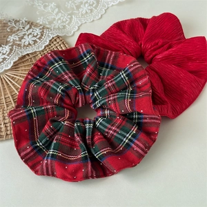 Detail of red plaid scrunchies with rhinestones and pleated fabric for Christmas hair style