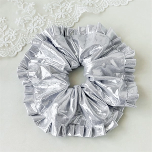 Detailed close-up of a silver metallic oversized scrunchie with layered pleated texture