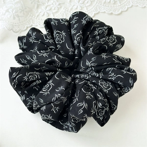 Detail of large ink floral scrunchie with white rose patterns on black chiffon fabric