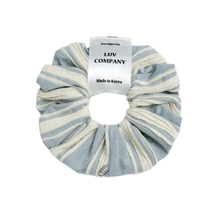 Elegant blue and white striped fabric scrunchie hair tie with metal logo and brand tag