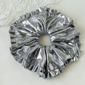 Detailed view of silver metallic oversized pleated scrunchie with ruffled edges