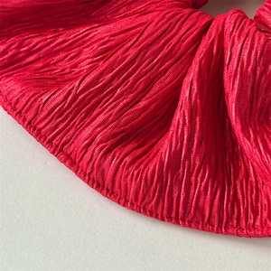 Detailed view of the red pleated fabric texture and craftsmanship of the large hair scrunchie