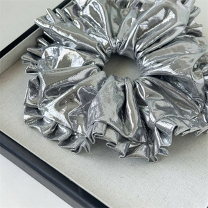 Close-up of metallic silver oversized scrunchie with layered pleated texture and shine