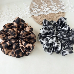 Detailed view of silk leopard print hair scrunchies in brown and grey patterns