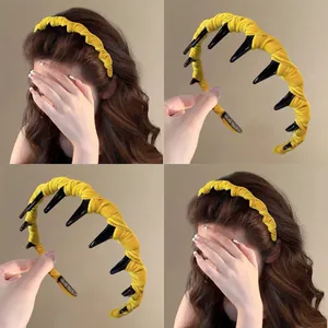Detail of yellow velvet pleated headband featuring long black inner teeth combs and handmade label