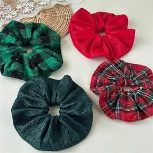 Detail of velvet red and green scrunchies with plaid patterns and glitter accents