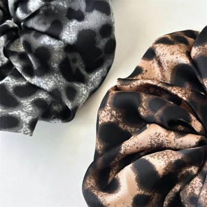 Detailed view of leopard print satin scrunchies showing fabric texture and pleats