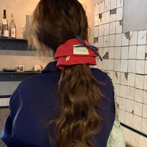 Detail of red fabric scrunchie with blue polka dot bow knot on long brown wavy hair